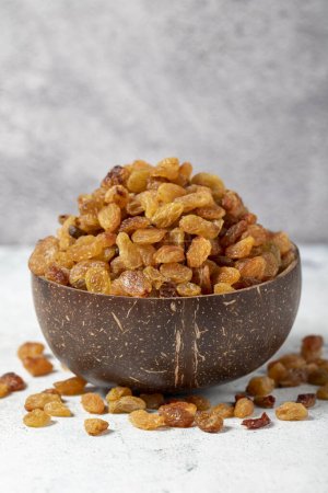 Téléchargez les photos : Raisins on stone background. Organic yellow raisins in a coconut bowl. Dried healthy nuts. close up - en image libre de droit