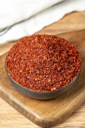 Photo for Red pepper flakes. Crushed chili pepper in bowl, dried chili flakes on wooden background. Close up - Royalty Free Image