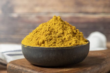 Foto de Curry Masala Powder. Turmeric powder or curry powder spice in a bowl on wooden background. indian spices. Dry spice concept. close up - Imagen libre de derechos