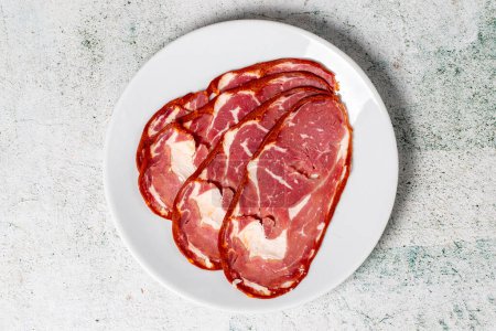 Photo for Beef ribeye bacon. Dried Turkish pastrami slices in plate. Traditional Turkish delicacies. Top view - Royalty Free Image