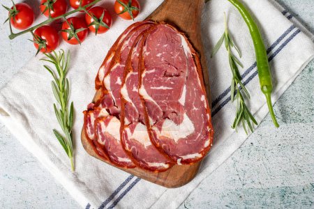 Photo for Beef ribeye pastrami. Slices of dried turkish bacon on a wooden serving board. Traditional Turkish delicacies. Local name pastirma. Top view - Royalty Free Image
