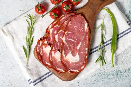 Photo for Beef ribeye pastrami. Slices of dried turkish bacon on a wooden serving board. Traditional Turkish delicacies. Local name pastirma. Top view - Royalty Free Image