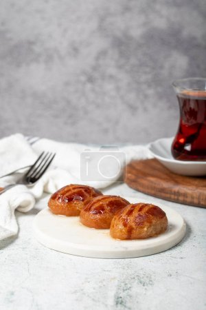 Sekerpare or bademdpare dessert. Turkish Ramadan dessert. Sekerpare dessert with sherbet on a marble serving plate
