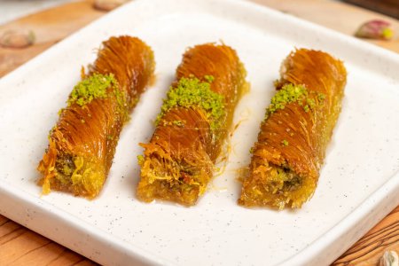 Kadayif with pistachios on a wooden background. Turkish cuisine delicacies. Ramadan Dessert. local name burma kadayif