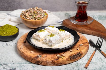 Photo for Baklava with white chocolate and milk. Cold baklava with chocolate on a wooden serving board. Famous dishes of Turkish cuisine - Royalty Free Image
