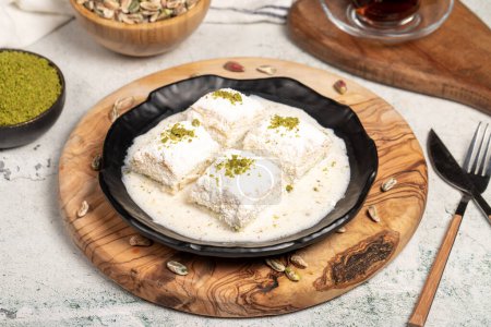 Photo for Baklava with white chocolate and milk. Cold baklava with chocolate on a wooden serving board. Famous dishes of Turkish cuisine - Royalty Free Image