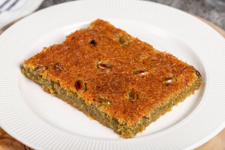 Kadayif dessert with syrup. Traditional Turkish cuisine desserts. Kadayif with pistachios on a wooden serving board