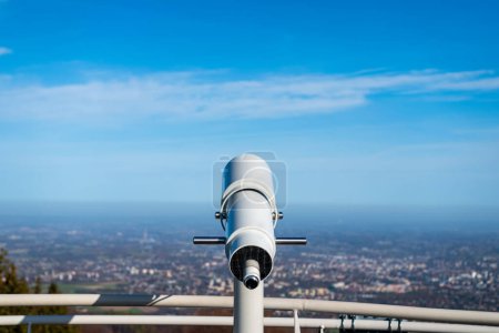 Telescope placed on viewing platform on Szyndzielnia Mountain in Bielsko-Biala, Poland. Railing of observation tower deck. Cityscape in the background. Blurred horizon. 