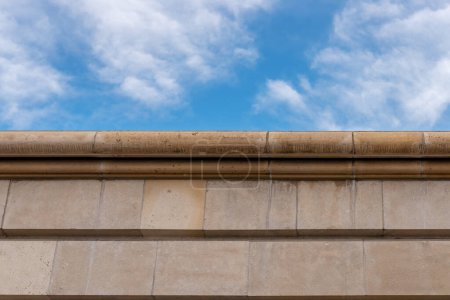 Foto de Stone wall made of dolomite against the blue sky. Rustication and cornice. Architectural detail - Imagen libre de derechos