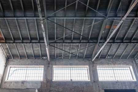 Foto de Gable roof truss of a large, vintage factory hall. Roofing construction (sheathing) made of wooden planks. Industrial interior. - Imagen libre de derechos