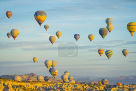 Téléchargez les photos : Vue panoramique de nombreuses ballons à air chaud de différentes couleurs et motifs survolant un paysage rocheux inhabituel en Cappadoce. Beau ciel matinal. Photo de haute qualité - en image libre de droit