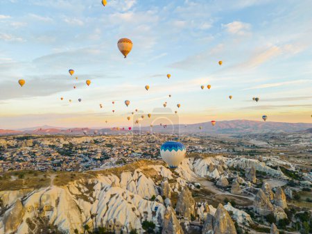 Téléchargez les photos : Vue à couper le souffle des drones de centaines de montgolfières au-dessus de la Cappadoce emblématique des dindes, des villes souterraines et de la vallée des cheminées de fées, des formations rocheuses, au lever du soleil. Photo de haute qualité - en image libre de droit