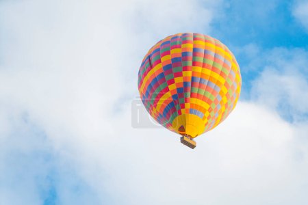 Téléchargez les photos : Montgolfière colorée à motifs volant sur le fond bleu ciel nuageux au-dessus de la ville turque de Cappadoce. Sports extrêmes et expériences pendant le voyage. Photo de haute qualité - en image libre de droit