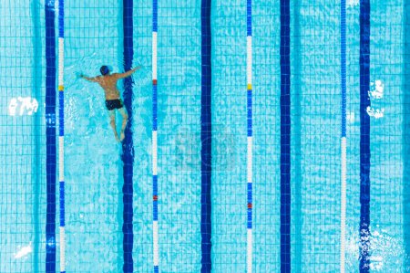 Top aerial view of one man swimming in the pool lane. High quality photo