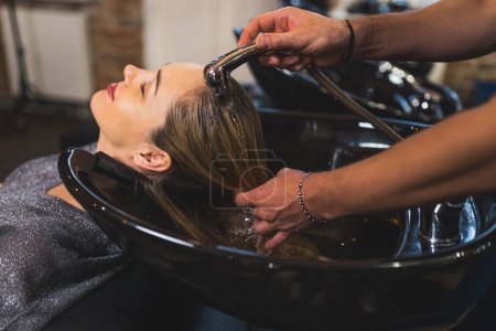Photo for Hairdresser washing clients hair at the salon, side view medium closeup, beauty concept. High quality photo - Royalty Free Image