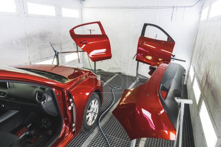Photo for A luxury red car in a paint shop with its doors removed for a fresh coat of paint. High-quality photo - Royalty Free Image