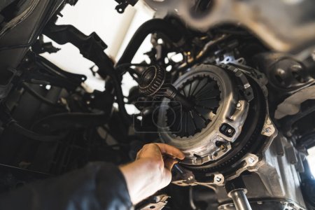 Foto de Closeup shot of an auto mechanic installing a new clutch kit for a car, auto repair shop. High quality photo - Imagen libre de derechos