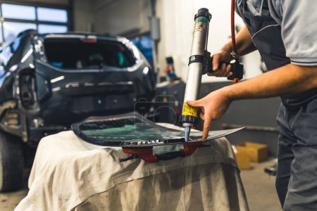 Photo for Worker applying an adhesive sealant to car windscreen preparing for replacement. High-quality 4k stock image. - Royalty Free Image