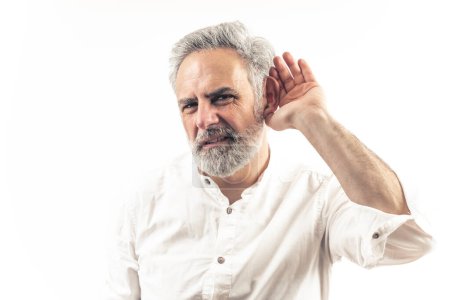 Téléchargez les photos : Homme aux cheveux gris de 40 ans écoutant avec la main sur l'oreille - Studio isolé gros plan. Photo de haute qualité - en image libre de droit