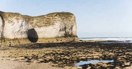 Photo for Flamborough Head beach. North Landing beach - beautiful expanse of sand, white pebbles and rock pools. Tourists silhouettes. High quality photo - Royalty Free Image