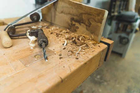 Foto de Soporte - vieja herramienta de carpintería en lugar de la máquina de perforación automática - colocado en la mesa de madera junto a las limaduras de madera. No hay gente. Copiar espacio. Foto de alta calidad - Imagen libre de derechos
