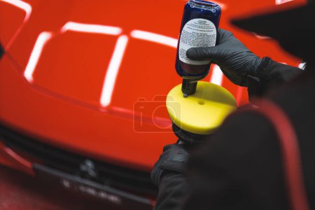 Applying polish on car. High angle closeup shot of professional car detailing worker distributing polishing product onto orbital car polish. High quality photo