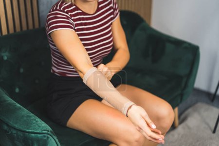 woman putting an elastic brace on her hand at home, injuries and self-treatment. High quality photo