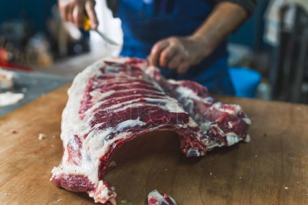 Photo for Butcher trying to pull or cut a piece of calf in a butcher shop. High quality photo - Royalty Free Image