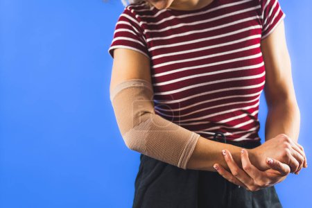 young woman with a bandage on her elbow over blue background. High quality photo