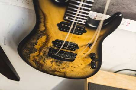 closeup shot of the modern bass guitar hanging on the wall, musical instrument concept. High quality photo