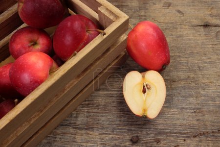 Small red Autumn Strawberry shaped Apple cut slice seed in wooden crate box on rustic wooden background  