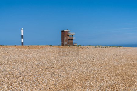 The beach with the Old Lifeguard Station and the New Lighthouse in Dungeness, Kent, England, UK