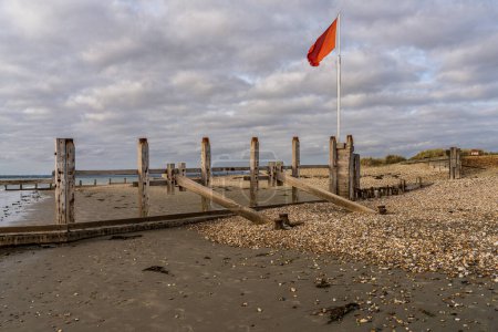 Nubes oscuras y una bandera roja en la playa de West Wittering, West Sussex, Inglaterra, Reino Unido