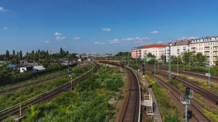 Photo for Berlin-Prenzlauer Berg, Germany - September 08, 2021: The city railway line seen from the Behmstrassenbruecke with the Bornholmer Street station in the background - Royalty Free Image