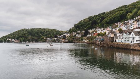 Téléchargez les photos : Dartmouth, Devon, Angleterre, Royaume-Uni - 26 mai 2022 : La rive de la rivière Dart avec quelques bateaux et la partie sud de Dartmouth - en image libre de droit