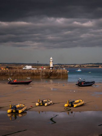 Téléchargez les photos : St Ives, Cornouailles, Angleterre, Royaume-Uni - 30 mai 2022 : Nuage sombre en soirée et bateaux dans le port à marée basse - en image libre de droit