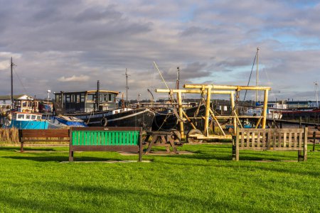 Photo for Pin Mill, Suffolk, England, UK - November 22, 2022: Benches at the harbour with a view of the boats - Royalty Free Image