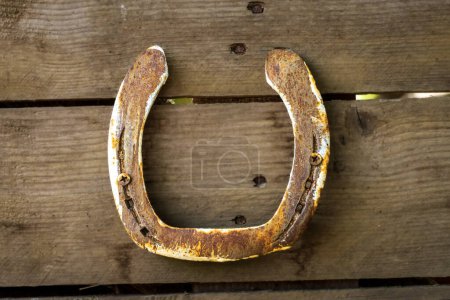 A rusty horseshoe screwed to a wooden wall