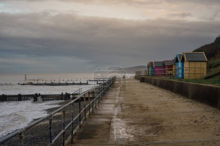 Nubes oscuras sobre las cabañas de la playa en Overstrand Beach, Norfolk, Inglaterra, Reino Unido