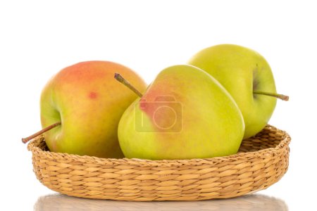 Photo for Three green sweet apples on a straw plate, macro, isolated on white background. - Royalty Free Image