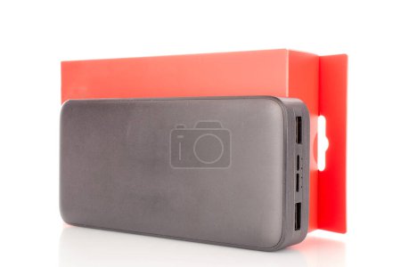 Téléchargez les photos : Un chargeur de banque d'alimentation portable noir avec boîte en papier rouge, gros plan isolé sur fond blanc. - en image libre de droit