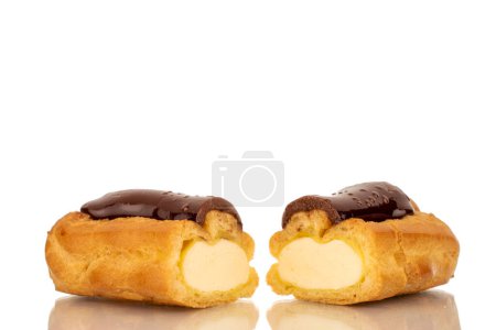 One sweet chocolate eclair cut in half, close-up, isolated on white.