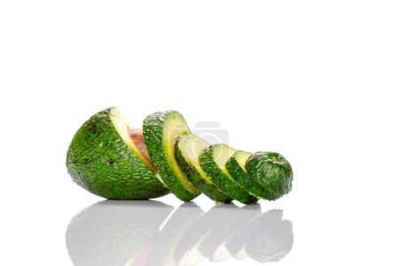 Photo for One dark green, delicious, organic avocado, cut across into several pieces, on a white background. - Royalty Free Image
