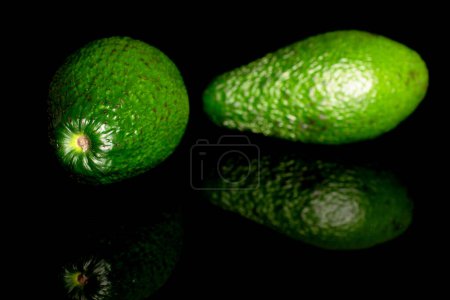 Photo for Two dark green ripe organic avocados, macro, isolated on black white background. - Royalty Free Image