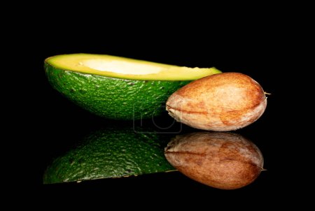 Photo for One half with a bone, cut along, green, ripe, dietary, delicious avocado, on a black background. - Royalty Free Image