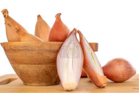 Photo for One organic onion cut in half and several whole in a wooden cup on a bamboo tray, macro, on a white background. - Royalty Free Image