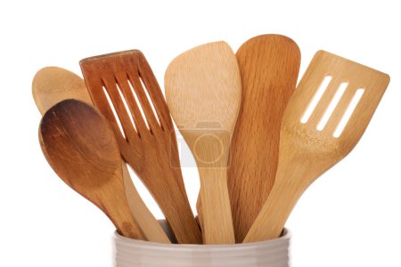 Foto de Varias cucharas de madera para la cocina en un plato de cerámica, macro, aislado sobre un fondo blanco. - Imagen libre de derechos