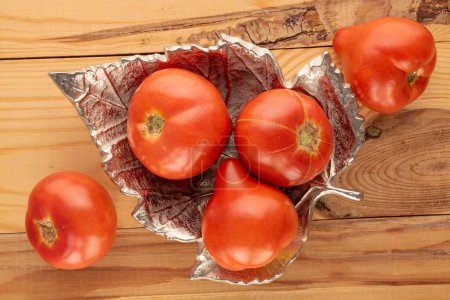 Photo for Several red tomatoes with a metal tray on a wooden table, macro, top view. - Royalty Free Image