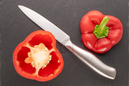 Foto de Dos mitades de pimiento rojo dulce con cuchillo de escoba en piedra de pizarra, macro, vista superior. - Imagen libre de derechos