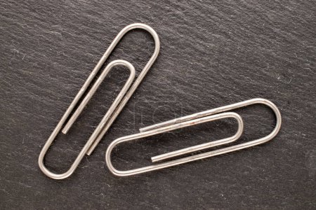 Photo for Two metal paper clips on slate stone, macro, top view. - Royalty Free Image